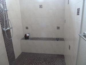 a bathroom with a shower with a tiled tub at Gîte Cosy Grand confort dans un écrin de verdure in Agudelle
