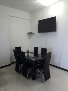 a black dining room table with black chairs and a flat screen tv at Beachurst Apartment in Durban