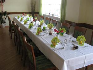 a long table with white table cloth and flowers on it at Gasthaus am Brunnen in Illerich
