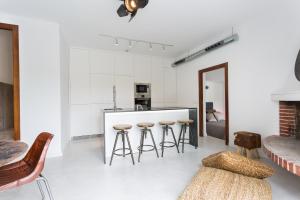 a white kitchen with bar stools and a counter at VILLA CAN MASS Architect Country Villa in Sant Rafael de Sa Creu