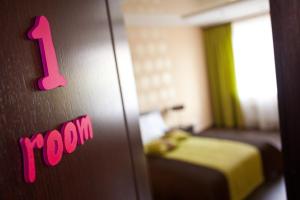 a room with a bed and a door with a pink sign at Easy Room in Nizhny Novgorod