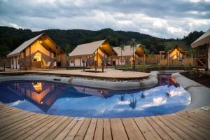 a pool with a wooden deck and some tents at Glamping Olimia Adria village in Podčetrtek