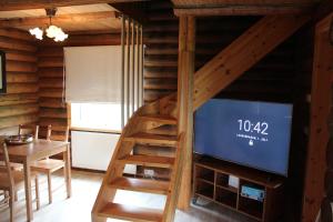 a living room with a tv and a wooden staircase at Akureyri Log Cottage in Akureyri