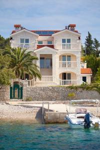 a large white house with a boat in the water at Villa Drinka Apartments in Vela Luka