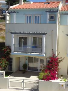 a white house with a balcony and flowers at Casa Senhor dos Passos in Nazaré