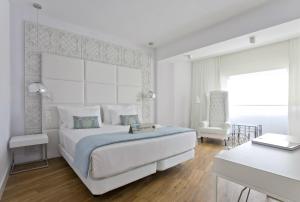 Hotel Tres Reyes Pamplona في بامبلونا: غرفة نوم بيضاء بسرير كبير وكرسي