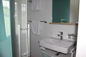een witte badkamer met een wastafel en een spiegel bij Landgasthof Grossteil in Giswil