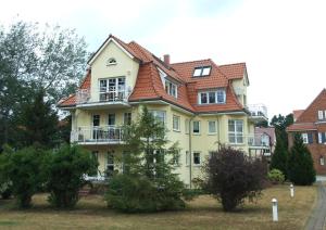 ein großes gelbes Haus mit rotem Dach in der Unterkunft Villa Kurpark Bad Saarow in Bad Saarow