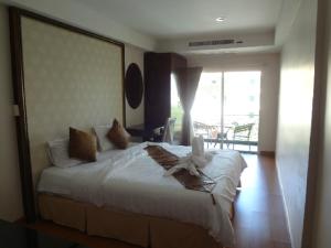 1 dormitorio con 1 cama blanca grande y balcón en Maleez Lodge, en Pattaya central