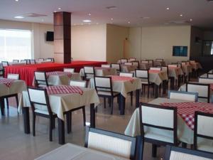 una sala da pranzo con tavoli, sedie e bancone rosso di Flamboyant Suite Hotel a Pôrto Velho