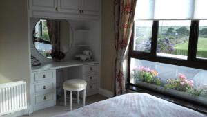 a bedroom with a mirror and a dresser and a window at Copperfield House B & B in Bunmahon