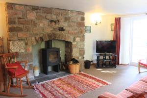 a living room with a stone fireplace and a tv at Church Hill Farm in Monmouth +7 photos