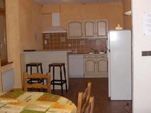 uma cozinha com uma mesa e cadeiras e um frigorífico em Gite Fouga em Aragnouet