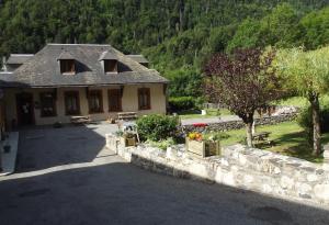a house with a stone wall in front of a yard at Gite Fouga in Aragnouet