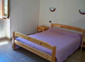 a bedroom with a wooden bed with purple sheets at Gite Fouga in Aragnouet