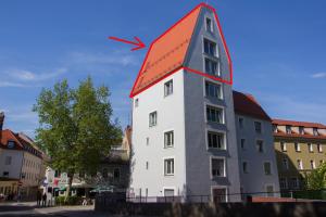 un grand bâtiment blanc avec un toit rouge dans l'établissement Stadtturm Regensburg, à Ratisbonne