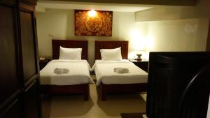 a bedroom with two beds and a tv at Swankaburi Boutique Hotel in Sawankhalok