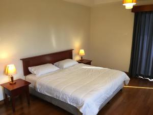 1 dormitorio con 1 cama grande, 2 mesas y 2 lámparas en Ian's Vacation Rental en Skudai