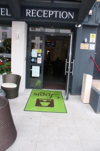 una entrada a un edificio con una alfombra verde de bienvenida en Logis Hôtel- Restaurant La Renaissance, en Baccarat
