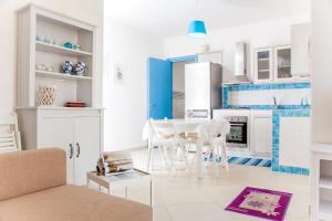 トッレ・ラピッロにあるVillino Pietra del Mareの白いキャビネット、テーブルと椅子付きのキッチンが備わります。