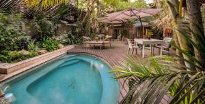 a swimming pool in a garden with a table and an umbrella at Zebrina Guest House in Nelspruit