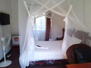 a bedroom with a white bed with a canopy at Kuku Royal Lodge in Ndola +30 photos