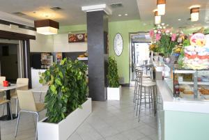 un restaurant avec des murs verts, des tables et des plantes dans l'établissement Hotel Etna, à Lignano Sabbiadoro