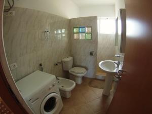a bathroom with a toilet and a sink and a washing machine at Casa Bahia 6 in Santa Maria