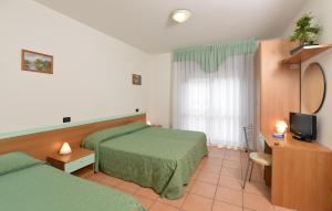 una camera d'albergo con due letti e una televisione di Hotel Etna a Lignano Sabbiadoro