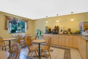 a kitchen with wooden tables and chairs and a counter at Super 8 by Wyndham Augusta in Augusta