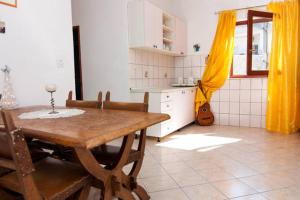 a kitchen with a wooden table and yellow curtains at Apartman 1 in Podstrana