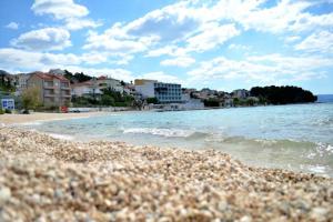 a beach with a rocky shore with buildings and the ocean at Apartman 1 in Podstrana