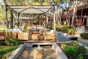 a patio with chairs and a fountain in a garden at Martı Myra - Ultra All Inclusive in Tekirova