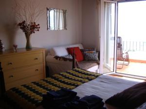 een slaapkamer met een bed, een bank en een raam bij Apartamento Charmoso no Funchal, com grande Jardim e Vista Esplêndida in Funchal