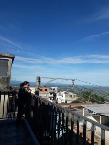 Una mujer parada en un balcón con vistas a la ciudad en Casas Label - Hospedagem São Thomé, en São Thomé das Letras