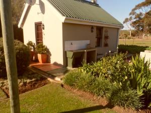 a small white house with a stove in the yard at Staandakkie Guest Cottage in Bredasdorp