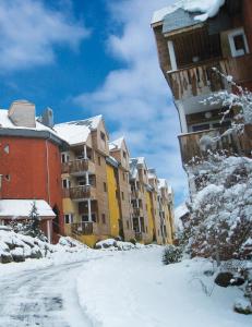una calle cubierta de nieve frente a un edificio en Lagrange Vacances Le Domaine des 100 Lacs en Cauterets