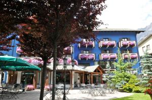 
a row of tables with umbrellas in front of a building at Hotel Baita Clementi in Bormio
