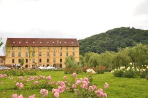 a large yellow building with a field of flowers at Hanul Moara cu Noroc in Ineu