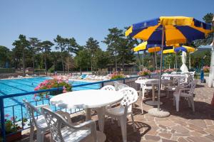 a patio with tables and umbrellas next to a pool at Camping Village Mare Pineta in Sistiana