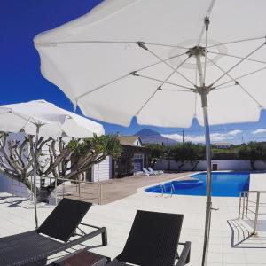 a patio with two chairs and an umbrella and a pool at Baia da Barca in Madalena