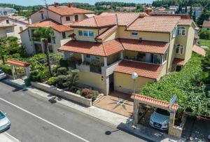 a large yellow house with red roofs on a street at Guesthouse Casa Nova in Poreč