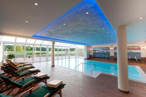 a large swimming pool with chairs and a large window at Golfpark Strelasund in Süderholz