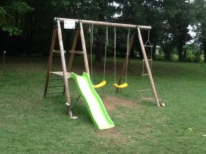 a playground with a green slide in a park at Camping Magali Plage in Liourdres