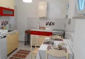 a kitchen with a table and chairs and a kitchen with red cabinets at Apartment Homey in Zadar