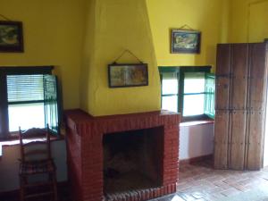 a living room with a brick fireplace and windows at Cortijo El Berrocal in Cazalla de la Sierra
