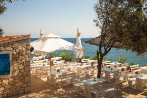 a group of tables and umbrellas and the ocean at Camping Village Poljana in Mali Lošinj