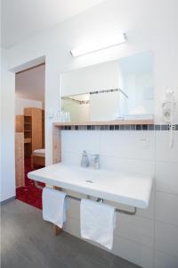 eine weiße Küche mit einem Waschbecken und einem Spiegel in der Unterkunft Hotel Vösenhuber in Ernsthofen