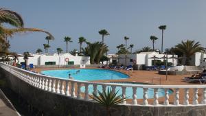 a swimming pool with a white fence and palm trees at Bungalow Franck in Puerto del Carmen