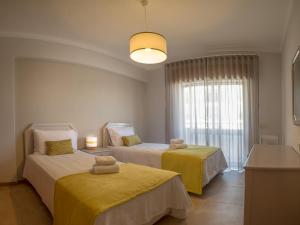 a bedroom with two beds with yellow sheets and a window at Flor Da Rocha in Portimão